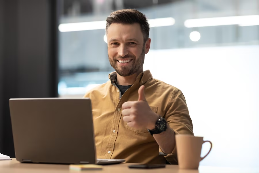 Man giving thumbs up near laptop