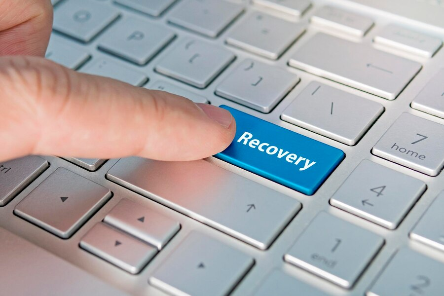Hand pressing a keyboard key with the text "recovery"
