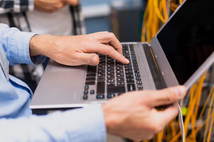 Close-up photo of a person’s hand typing on a laptop